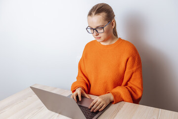 A girl with glasses is sitting at a laptop