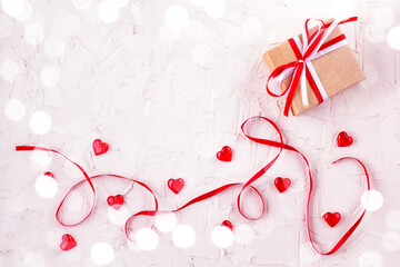 Gift box with red and white bow ribbon and hearts on white table for Valentines day