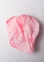 Creased piece of pink tissue paper on white background