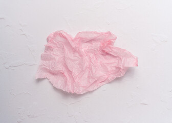 Creased piece of pink tissue paper on white background