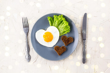 Valentines day breakfast with heart shaped fried eggs served on grey plate