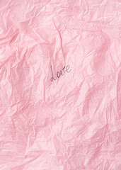 Fototapeta premium Word Love on a Creased piece of pink tissue paper