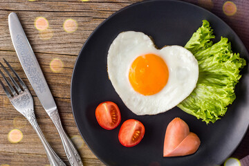Valentines day breakfast with heart shaped fried eggs served on grey plate.