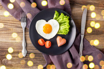 Valentines day breakfast with heart shaped fried eggs served on grey plate.