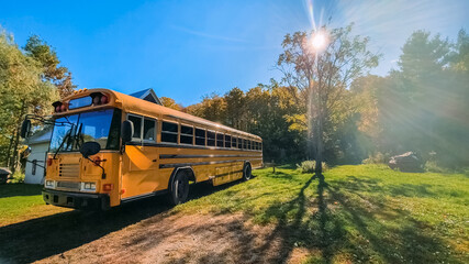 Wide angle view of a beautiful, vintage bright yellow bus parked in a lawn in the countryside,...