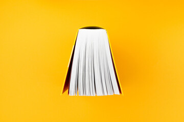 top view of big book with yellow cover on orange background