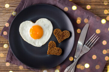 Valentines day breakfast with heart shaped fried eggs served on grey plate and napkin