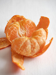 Fresh juicy bright orange tangerines with green leaves on a white cotton tablecloth in the morning light