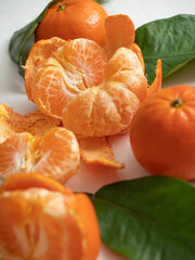 Fresh juicy bright orange tangerines with green leaves on a white cotton tablecloth in the morning light