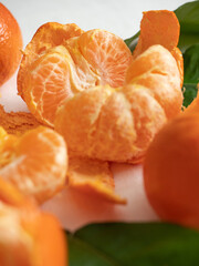 Fresh juicy bright orange tangerines with green leaves on a white cotton tablecloth in the morning light