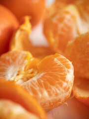 Fresh juicy bright orange tangerines with green leaves on a white cotton tablecloth in the morning light