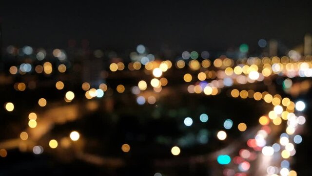 Blurred night light - Beautiful glittering bokeh in dark blurry background at night. Blurry photo at night time. 4K cityscape.