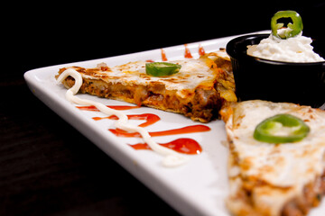 Comida mexicana, com deliciosa culinária mexicana, construção 45º sobre fundo preto. Nachos, burritos, guacamole, tacos, pimenta etc.