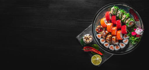 set of sushi roll with salmon, avocado, cream cheese, cucumber, rice, caviar, eel in plate on black wooden table background