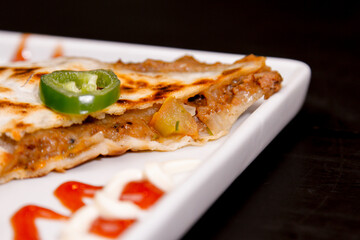 Comida mexicana, com deliciosa culinária mexicana, construção 45º sobre fundo preto. Nachos, burritos, guacamole, tacos, pimenta etc.