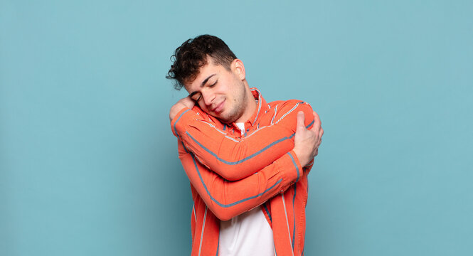 young man feeling in love, smiling, cuddling and hugging self, staying single, being selfish and egocentric