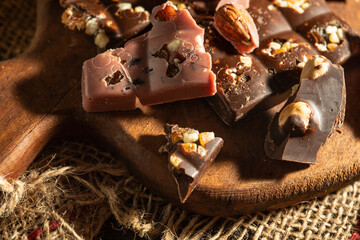 Pieces of pink and dark chocolate on rustic wooden background