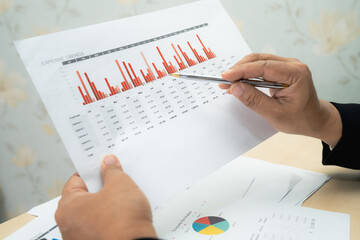 Asian accountant working and analyzing financial reports project accounting with chart graph and...