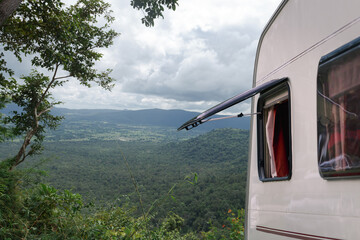 Close up part of camper van or caravan truck with window open parking at view point stop. Green relax freedom with nature mountain background