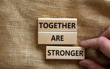 Together are stronger symbol. Concept words 'Together are stronger' on wooden blocks on a beautiful canvas background. Businessman hand. Business, motivational and together are stronger concept.