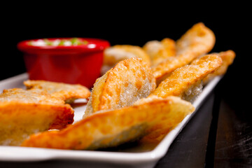 Deliciosos pasteis de carne, camarão, queijo com creme de queijo gorgonzola em recipiente branco em fundo escuro.