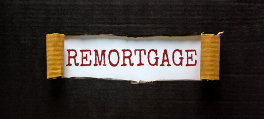Remortgage symbol. The word 'remortgage' appearing behind torn black paper. Beautiful black background. Business and remortgage concept.