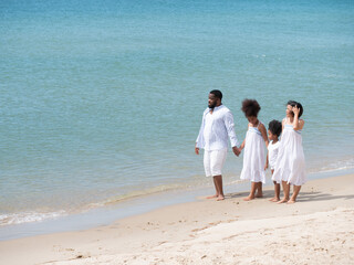 Happy African Asian family walking together at the beach on a beautiful day.