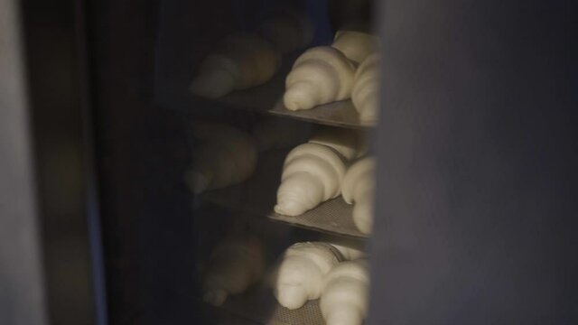 Process of baking tasty croissants are lied on racks in rotating oven