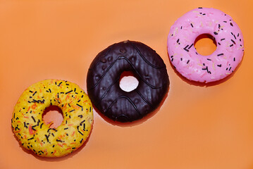 Colorful glazed donuts on a yellow background