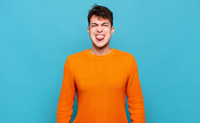 young man feeling disgusted and irritated, sticking tongue out, disliking something nasty and yucky