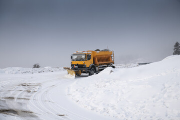 Snow plough truck cleaning a road through the mountains after winter massive snowfall