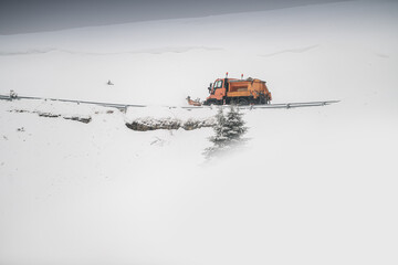 Snow plough truck cleaning a road through the mountains after winter massive snowfall