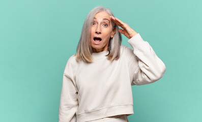 middle age woman looking happy, astonished and surprised, smiling and realizing amazing and...