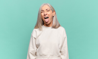 middle age woman with cheerful, carefree, rebellious attitude, joking and sticking tongue out,...