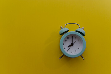Mint-colored alarm clock on a bright yellow background