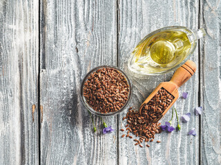 Flax seeds and flax oil. Brown linen seeds and flaxseed oil on old gray wooden background. Copy space. Top view or flat lay.