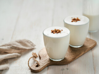 Kefir, buttermilk or yogurt with granola. Yogurt in glass on white wooden background. Probiotic cold fermented dairy drink. Gut health, fermented products, healthy gut flora concept. Copy space