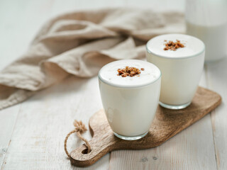 Kefir, buttermilk or yogurt with granola. Yogurt in glass on white wooden background. Probiotic...