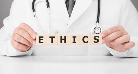 Doctor holds wooden cubes in his hands with text Ethics