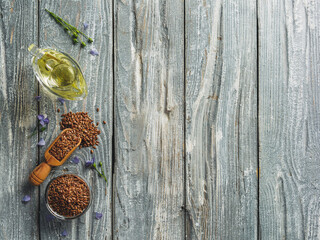 Flax seeds and flax oil. Brown linen seeds and flaxseed oil on old gray wooden background. Copy space. Top view or flat lay.