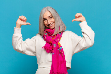 middle age woman feeling proud, arrogant and confident, looking satisfied and successful, pointing...
