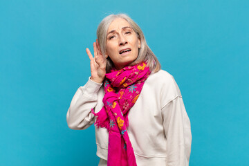 middle age woman looking serious and curious, listening, trying to hear a secret conversation or...