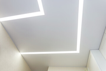 Fototapeta premium suspended ceiling with halogen spots lamps and drywall construction in empty room in apartment or house. Stretch ceiling white and complex shape.