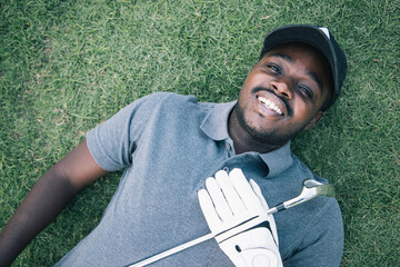 African American of young man and happy making selfie photo while laying on grass with golf putters...