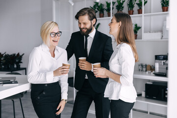 Happy work team during a break in the office drink tea, laugh, joke, enjoy communication.