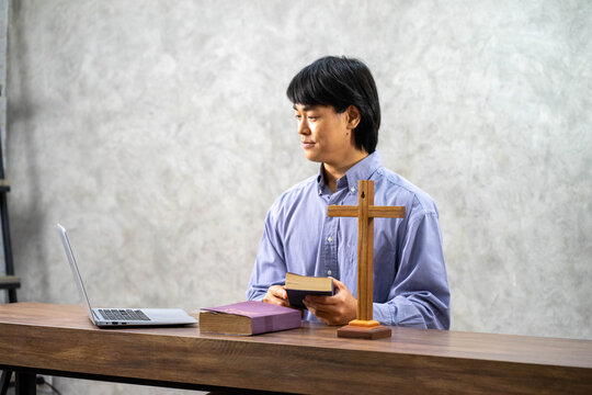 Asian Reverend teaching Christian praying with notebook and HOLY BIBLE in church