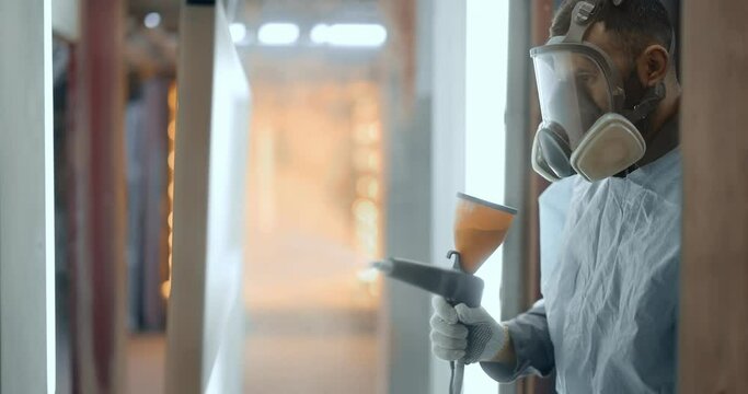 Painter in protective wear paints metal products with powder paint. Powder coating process at the manufacturing