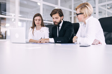 Fototapeta premium a serious male leader with his colleagues sits at the table and