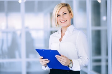 Happy beautiful young business woman standing and holding folder