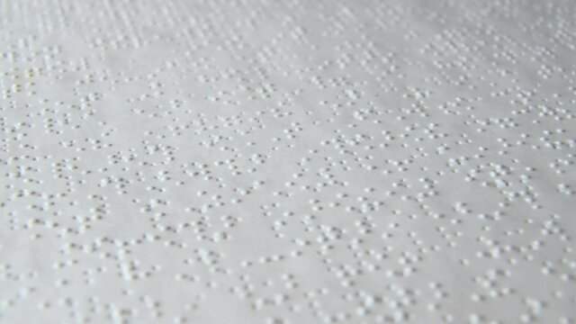 Braille Alphabet Printed Paper Slowly Rotating close up. Visually impaired book. Aid for the blind.